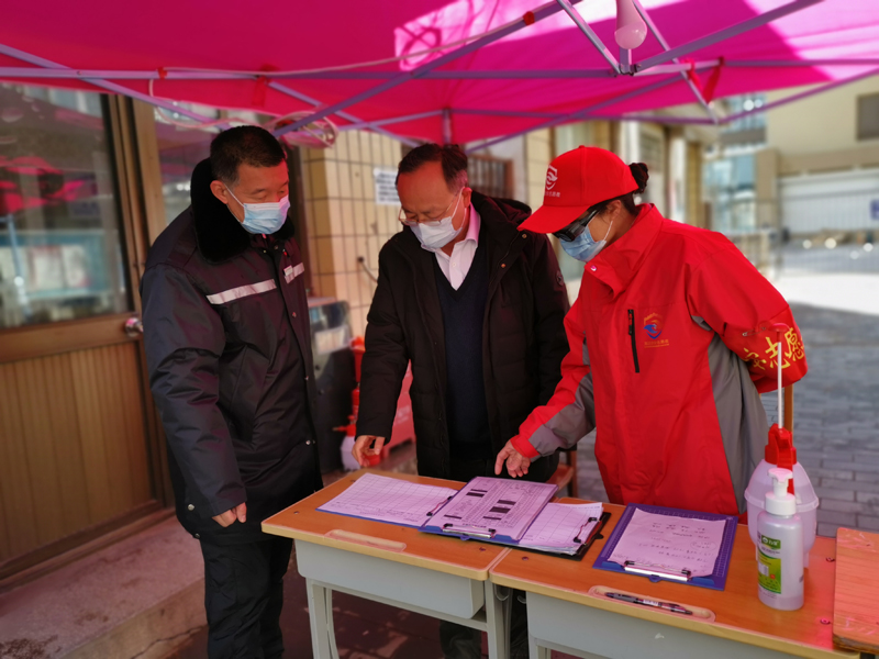 北京舞蹈学院校领导与老党员志愿者仔细查看家属区防疫登记记录